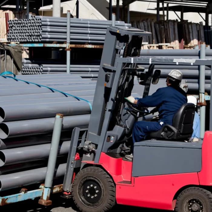 Forklift driver moving bundles of PVC electrical conduit
