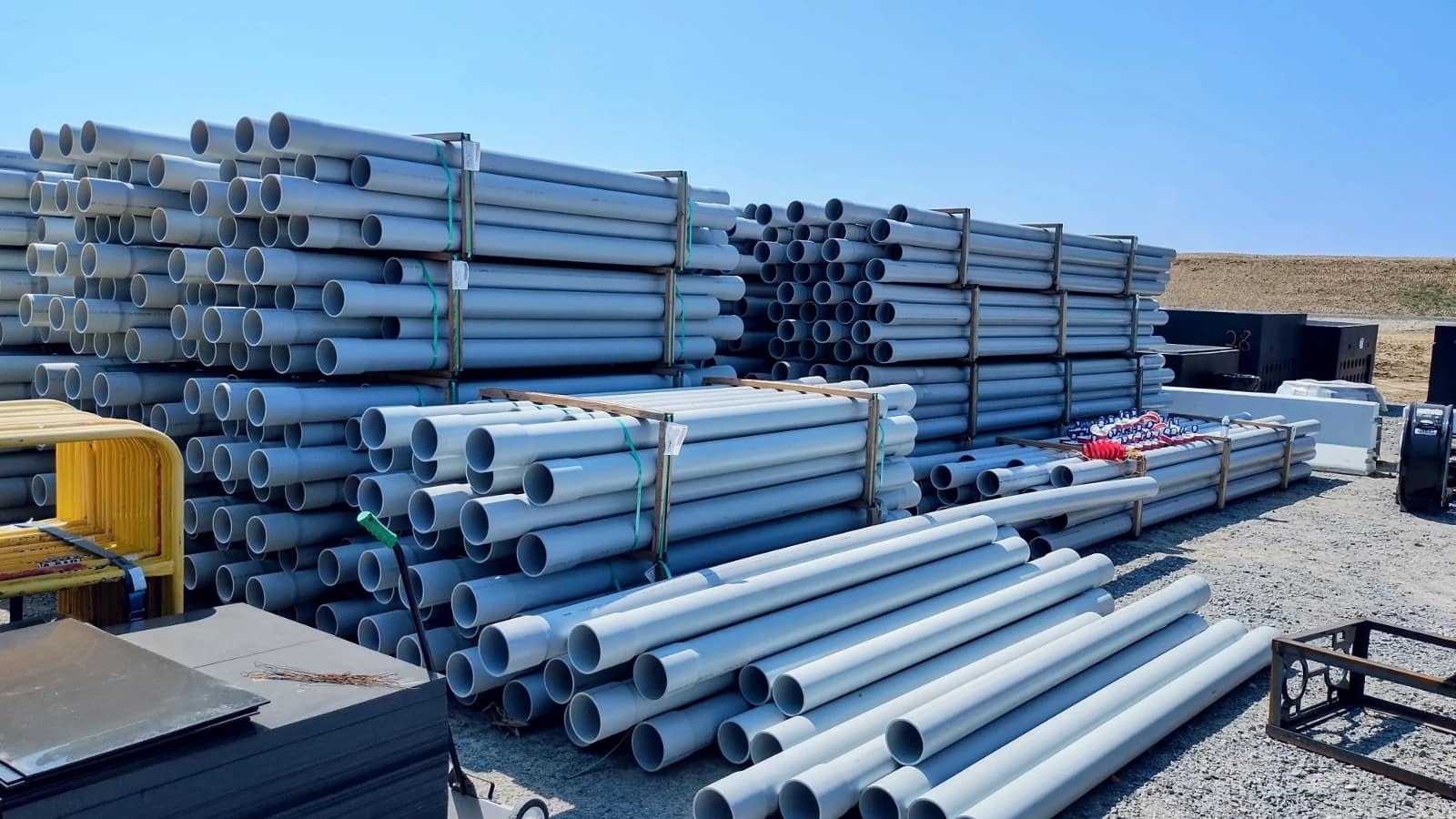 Stacks of Schedule 40 6 inch PVC electrical conduit bundles stored on a jobsite.